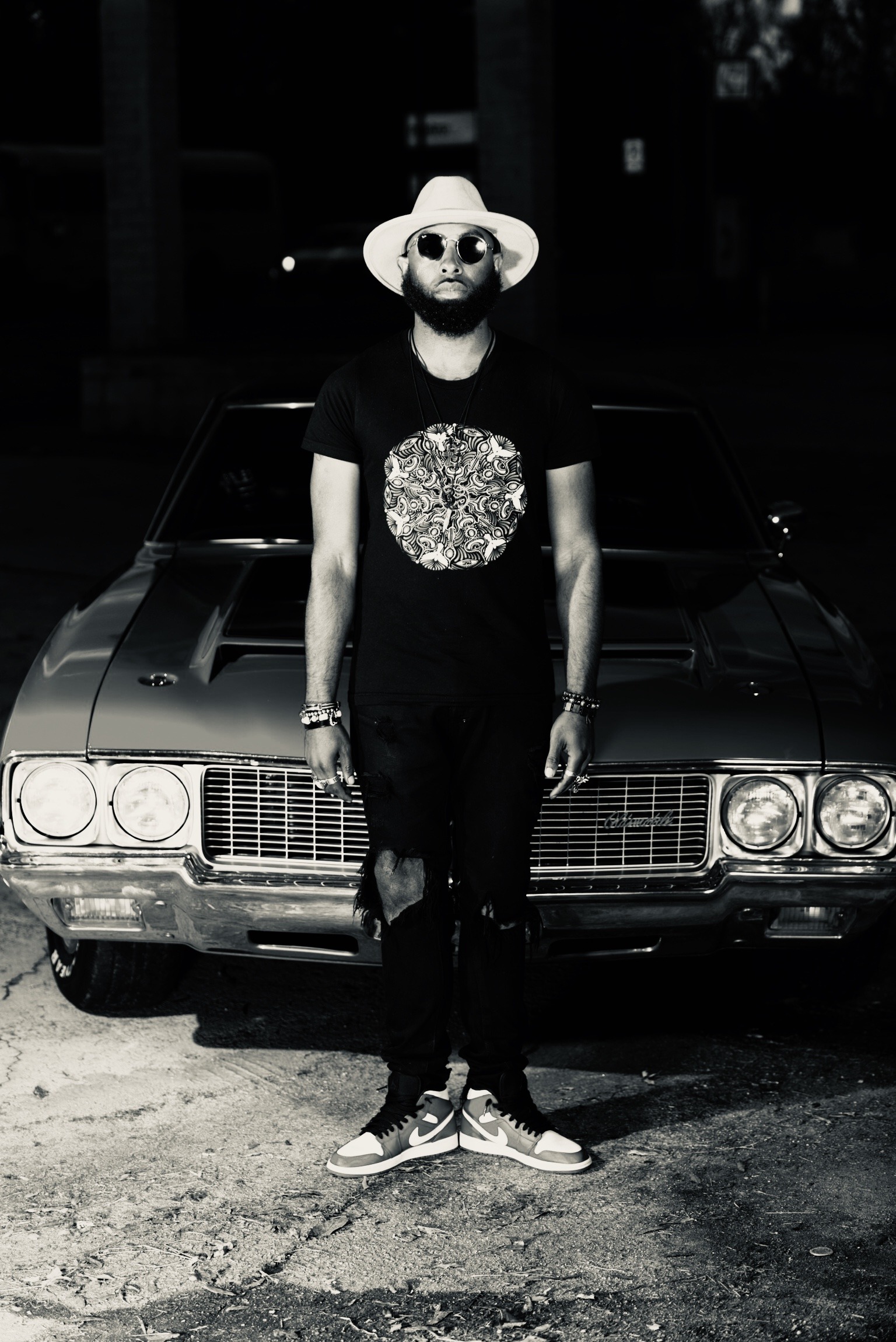 Black-and-white portrait of Hymnal Star standing in front of a classic car