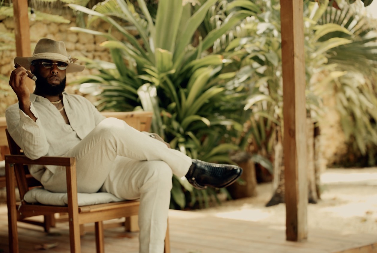 Hymnal Star seated in white clothing among tropical plants